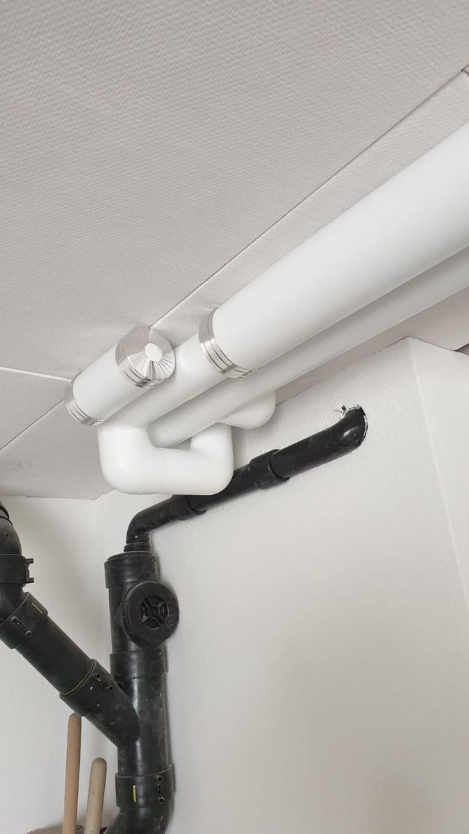Isolierte Leitung entlang einer Decke neben einer schwarzen Abwasserleitung