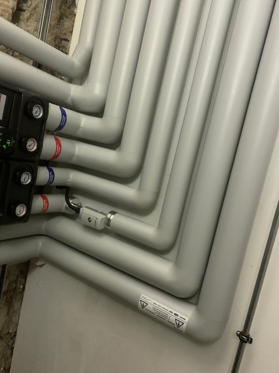 Heizungsverteiler mit isolierten Leitungen an einer Kellerwand